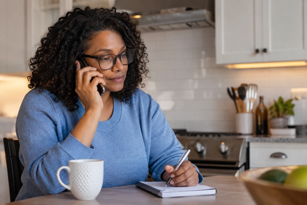 Woman making a phone call beside a notebook